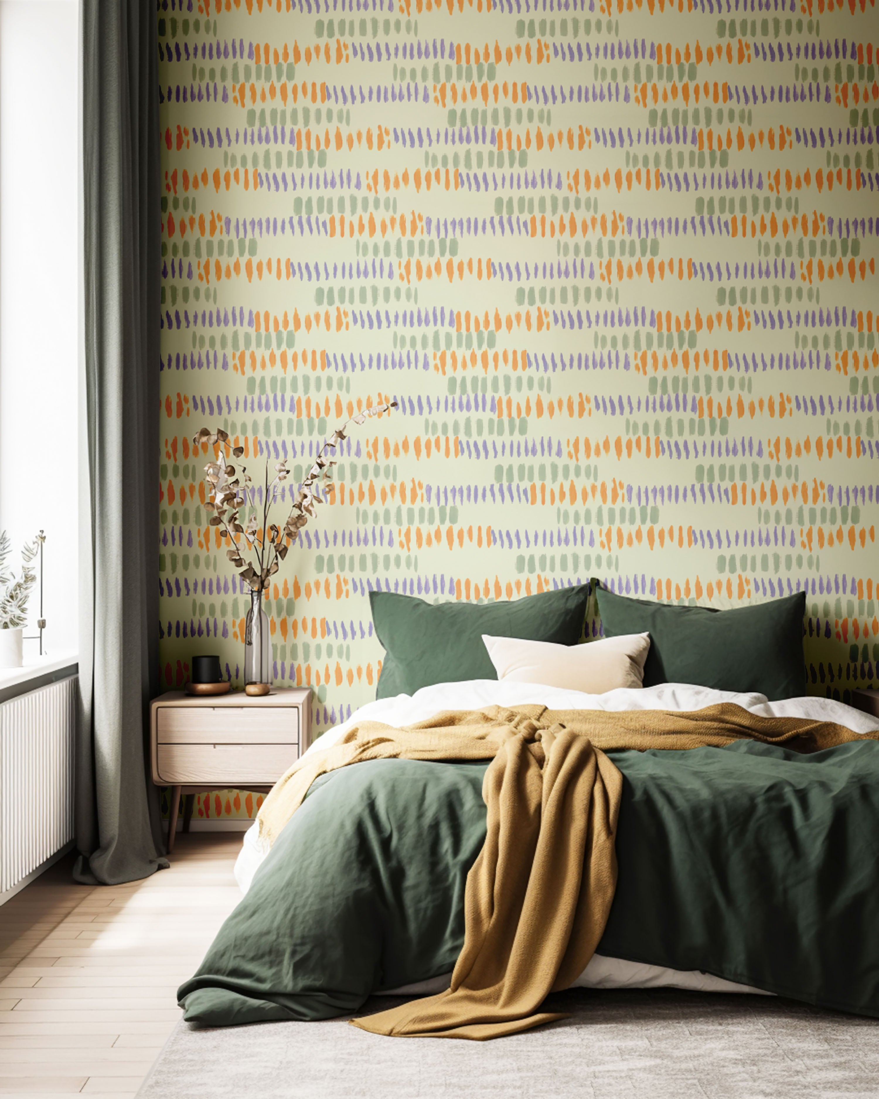 A bedroom with a wall featuring a repeating abstract geometric pattern by Terri Madden Studio in shades of orange, yellow, and green.