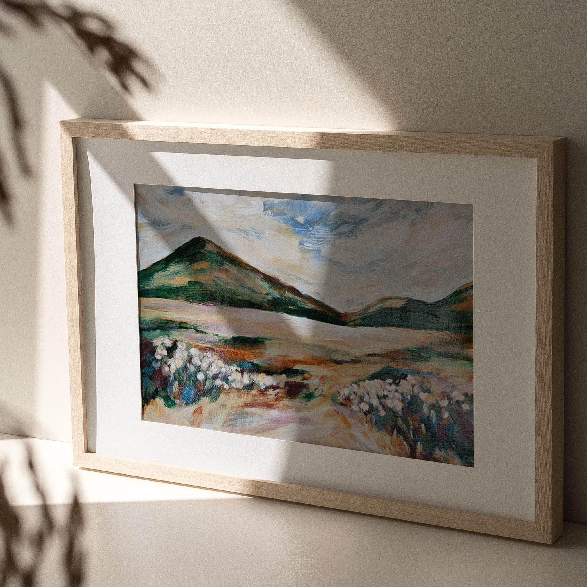 Framed painting of a mountain landscape by Terri Madden on a neutral wall