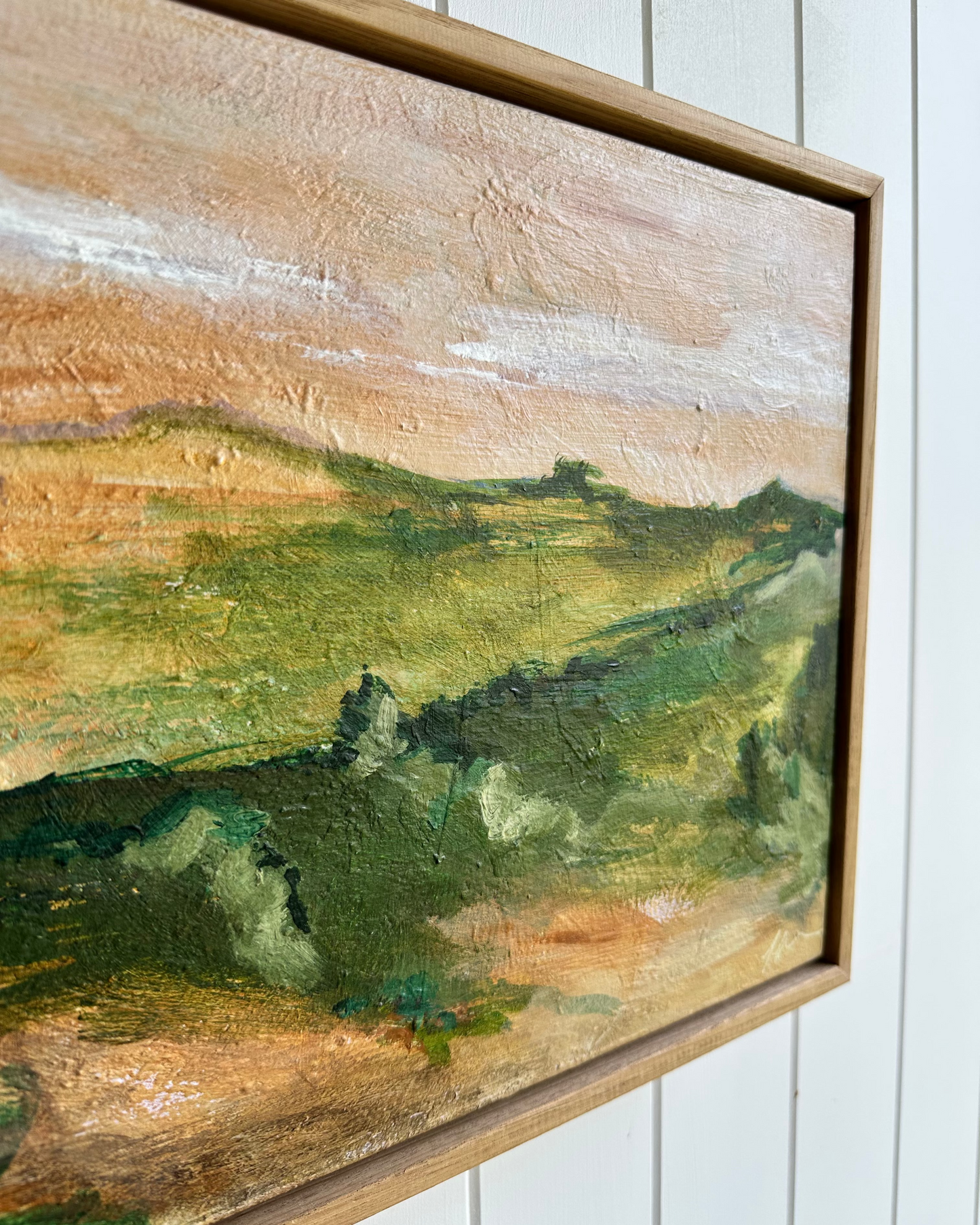 Framed landscape painting with a wooden frame on a white wall