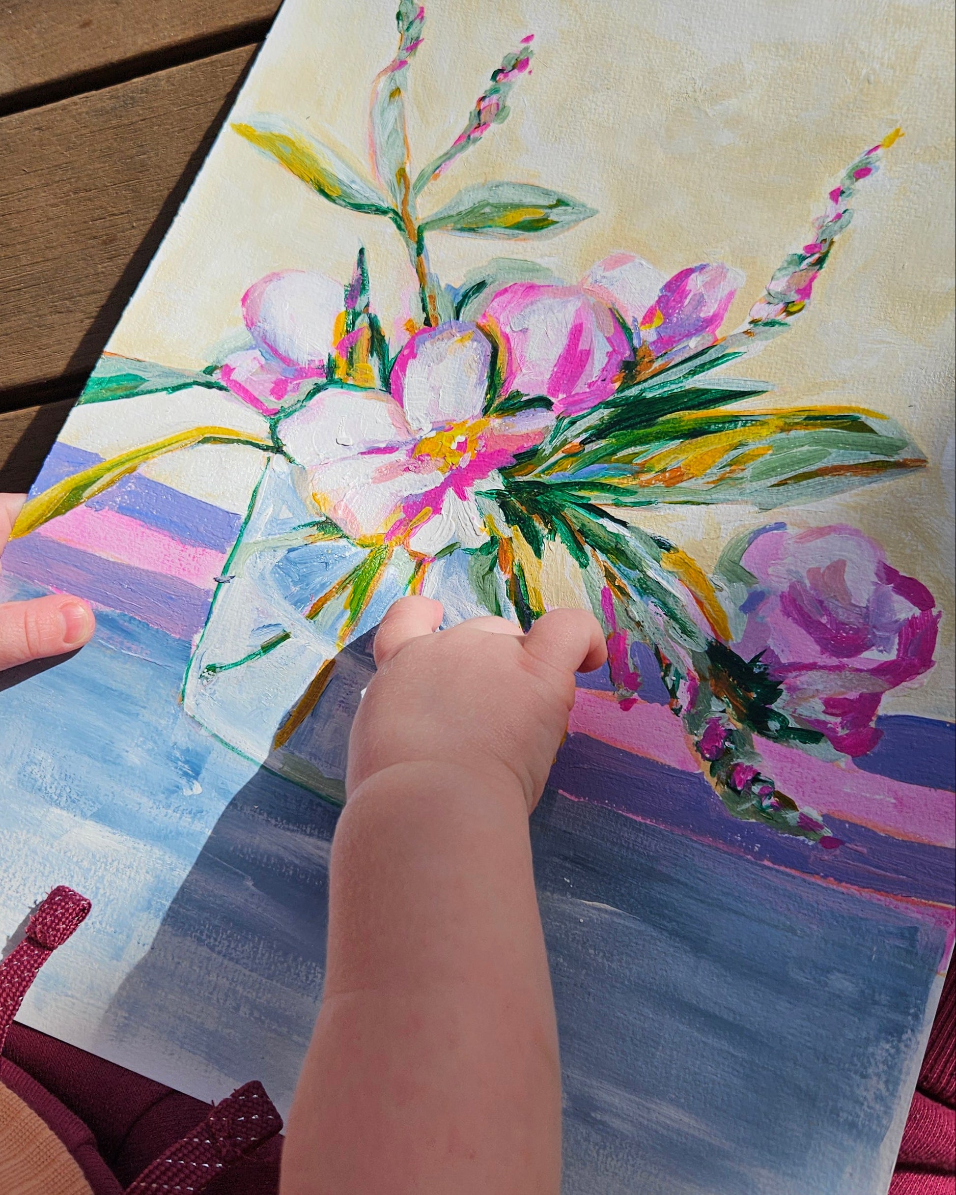 baby holding floral painting
