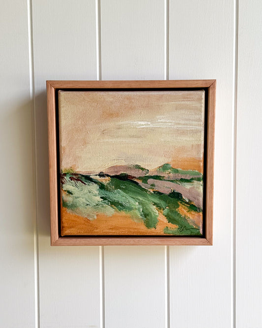 Framed landscape painting on a white paneled wall